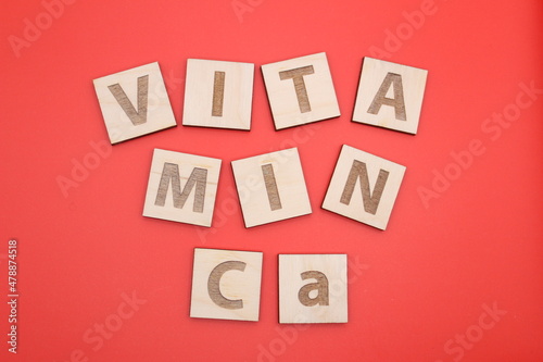 Wood cube letters Vitamin Ca with copy space on the red background