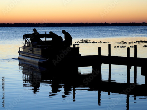Silhouette of Three Retired Men Heading Out for a Day of Fishing in Their Pontoon Boat at Sunrise