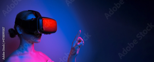 woman in vr glasses stretching her finger to touch something in virtual world