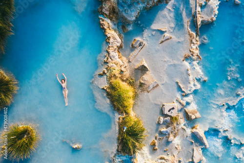 Beautiful woman in color swimsuit floating in hot springs on a sunny day