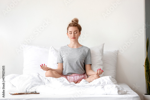 Morning of beautiful woman meditating on bed