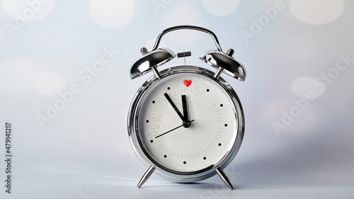 valentine's day concept, red heart at 12 o'clock, vintage alarm clock on a blurred bokeh background 