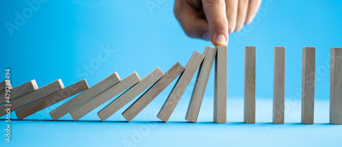 Businessman Stopping The Effect Of Domino With Hand