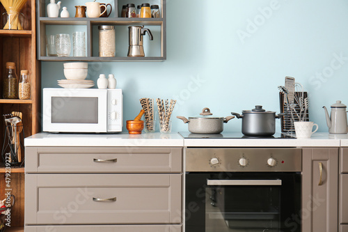 Interior of stylish kitchen with counter, microwave oven and shelves