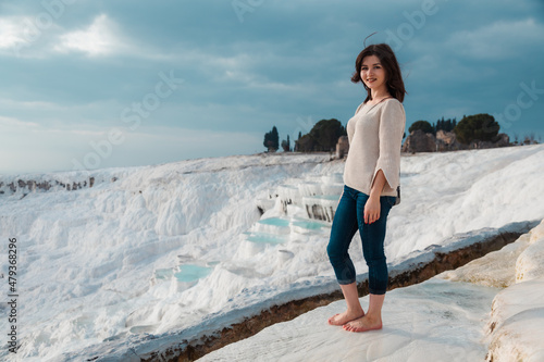 Woman standing barefoot and looking at the travertine pools in Pamukkale Turkey