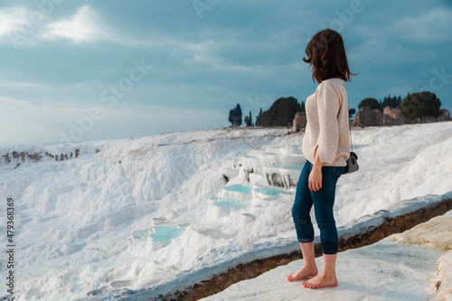 Woman standing barefoot and looking at the travertine pools in Pamukkale Turkey