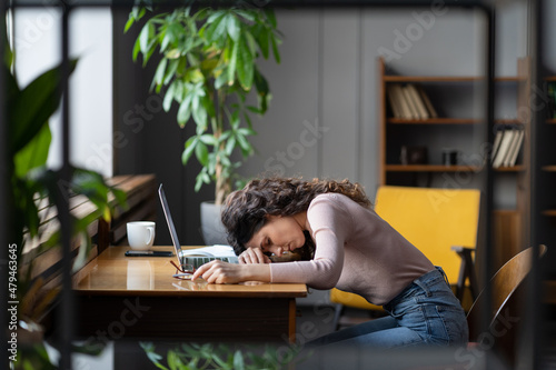 Tired businesswoman sleeping on table in office. Young exhausted girl lying on laptop keyboard, overwork unmotivated with monotonous tasks need rest. Unhappy freelancer female suffer from burnout