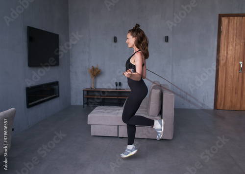 Girl exercising with jumping rope at home. Fit woman skipping rope.