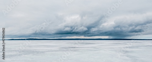 Frozen forest lake on a cloudy day. Dramatic sky after a blizzard. Onega, Karelia, Russia.Atmospheric winter landscape. Panoramic view. Nature, climate change, christmas vacations, eco tourism
