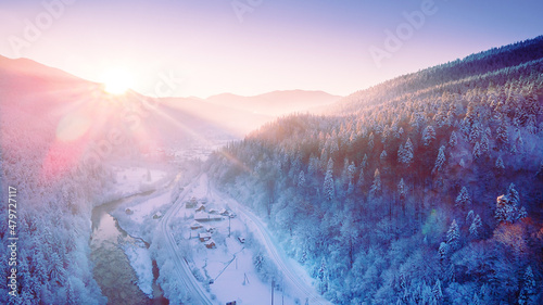 Stunning sunrise over snowy mountains in the alps, norway, finland, ukraine, the sun's rays penetrate through the trees. Mountains and snow, skiers go to the mountains.