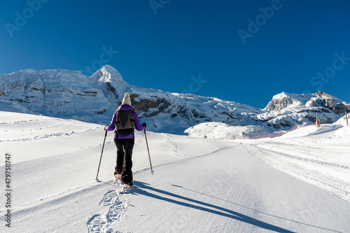 A young girl with snow rackets, walks through a completely snowy landscape in the Pyrenees mountain range (Spain).