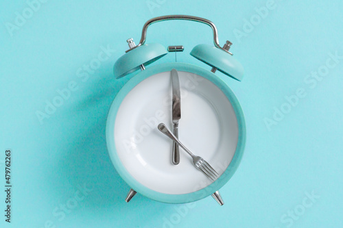 intermittent fasting concept - blue alarm clock, top view