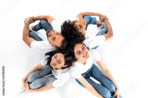 top view of happy multiethnic friends sitting back to back on white.