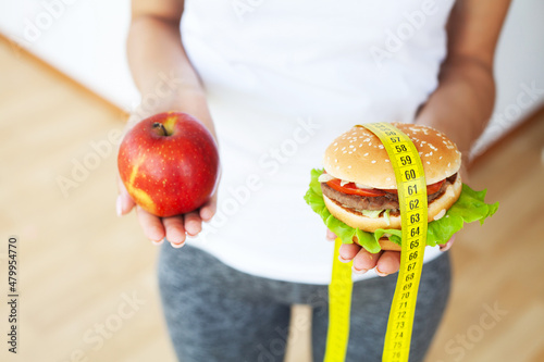 Diet concept, woman holding a choice of harmful hamburger and fresh apple.