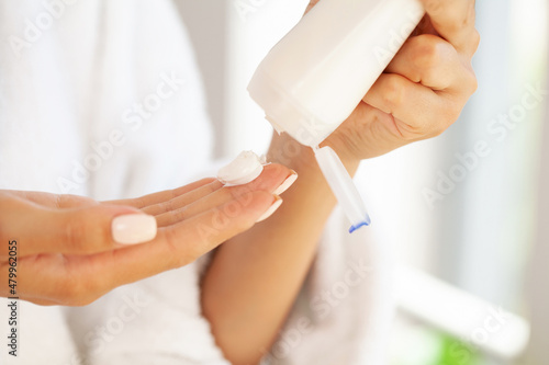 Closeup woman applying protective cream on hands.