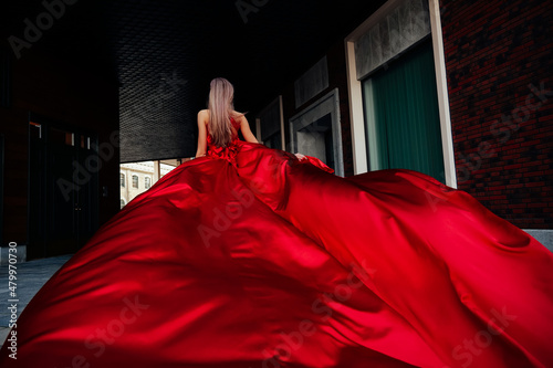 Young gorgeous woman in long red dress walking in the city