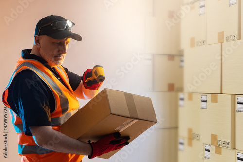Warehouse worker with data collection terminal. Man scans Barcode on package. Employee fulfillment center. Laser data collection terminal in hand of logistician. Man in warehouse of boxes.