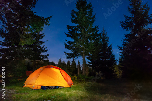 Illuminated tent in night forest