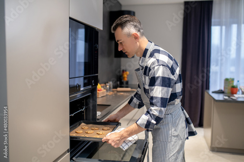 Man putting baking sheet in oven
