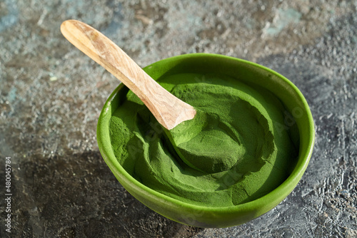 Green chlorella algae powder in a bowl with a spoon