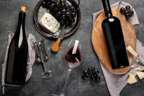 Red wine assortment with appetizers on gray background.