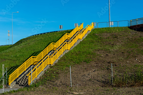 Schody z żółtymi barierami prowadzące do błękitnego nieba.