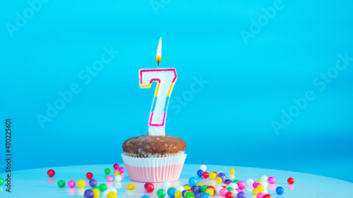 Beautiful birthday greetings to a seven year old child on a blue background, a card with the number 7 years happy birthday copy space. Festive children's background with cream cake