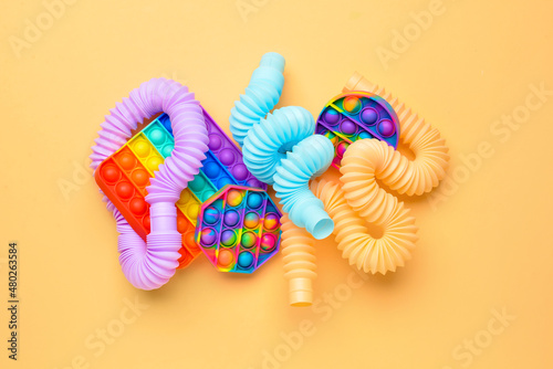 Colorful Pop Tubes and Pop it fidget toys on beige background