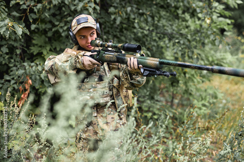 confident military woman l with rifle with an optical sight. Female chase sport hunter in forest with weapon in wild nature alone, looking through the sight. sport, military, army, hunter concept
