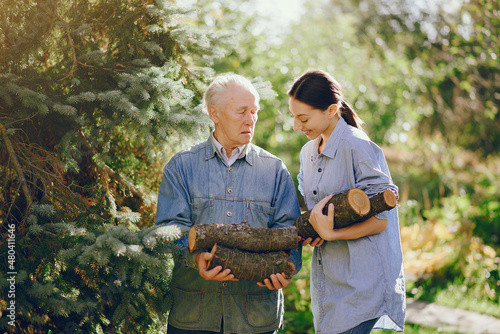 Grandfather with granddaughter on a yard with firewood in hands