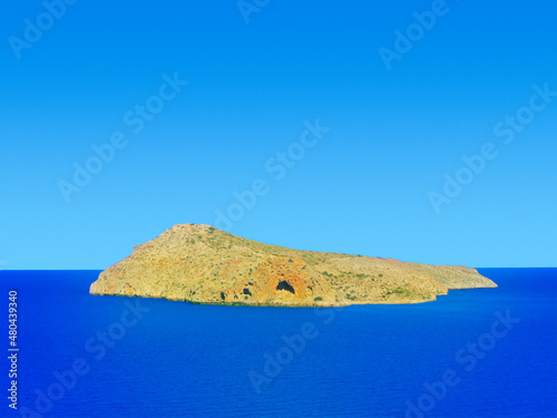 Near Crete, Greece. Agios Theodoros island is isolated on navy blue sea and clear blue sky in sunny day. Currently, this island is a national reserve for goats Kri-Kri.