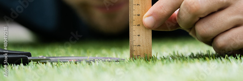 Man Using Measuring Scale While Cutting Grass