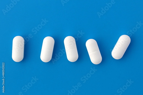 Five white oblong tablets lie on a blue background.