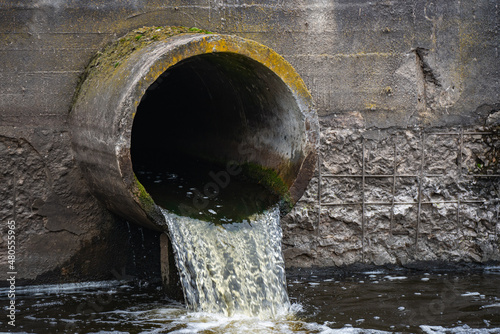 Dirty water flows from the pipe into the river, environmental pollution. Sewerage, treatment facilities