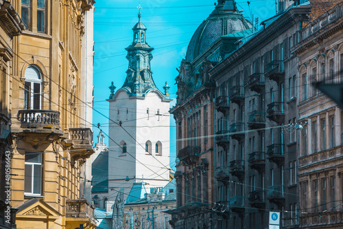 view of lviv street with cathedral church tower between buildings