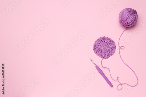 Knitting and crochet hook on pink background, flat lay. Space for text