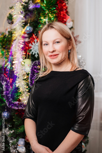 a beautiful blonde woman in a black dress by the Christmas tree. a single unmarried woman. dating site. happy Christmas holidays. cosmetology and medicine for women.