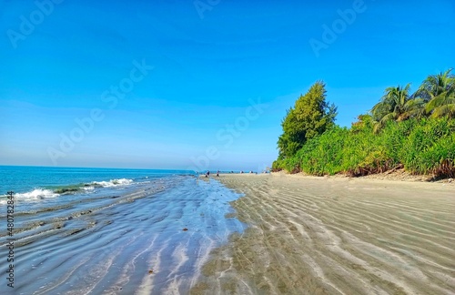 Open beach with trees, Blue sky and water.