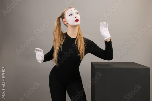 Circus girl, mime artist near the black cube.