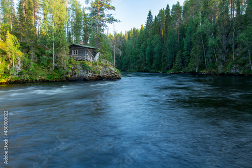 Kitka river landscape with a wooden cottage on the riverbank by Pieni Karhunkierros hiking trail in Oulanka national park, Northern Finland, Europe.