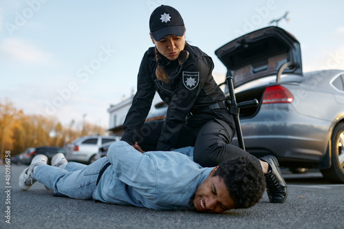 Police officer arresting suspicious young car driver