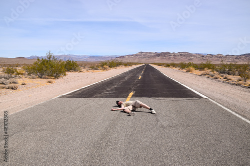 A man pretending to lay in the middle of a highway in the Death Valley