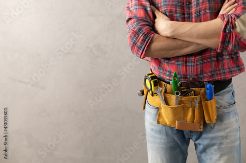 Worker man with tool belt near concrete or cement wall. Male hand and tools for house renovation