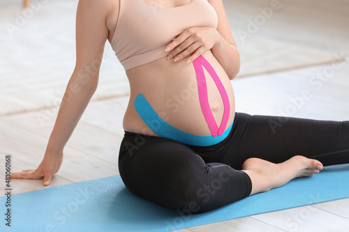Pregnant woman with applied kinesio tape training at home