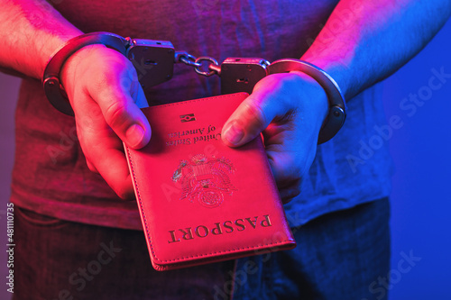 Hands in handcuffs with an American passport, the concept of punishment for fake documents