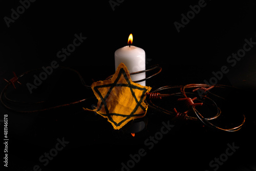 Holocaust memory day. Arbed wire and burning candle on black background