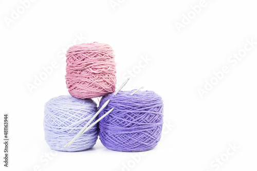 Ovillos de lana con agujas para tejer sobre un fondo blanco liso y aislado. Vista de frente y de cerca. Copy space