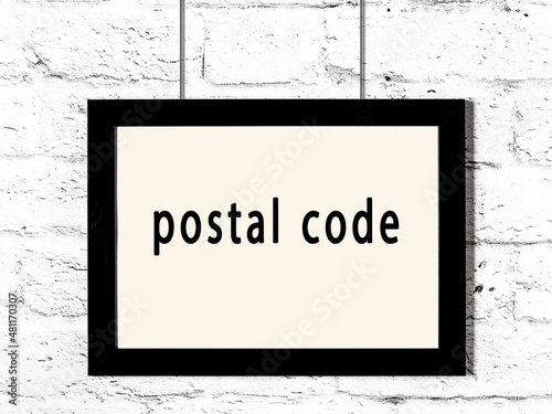 Black frame hanging on white brick wall with inscription postal code