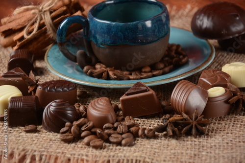 Coffee cup, beans, chocolate on old kitchen table Assortment of dark, white and milk chocolate sweets, zefir (zephyr). Spices, cinnamon.