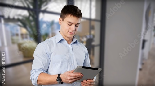 Young marketing business manager expert standing in modern corporate office using digital tablet